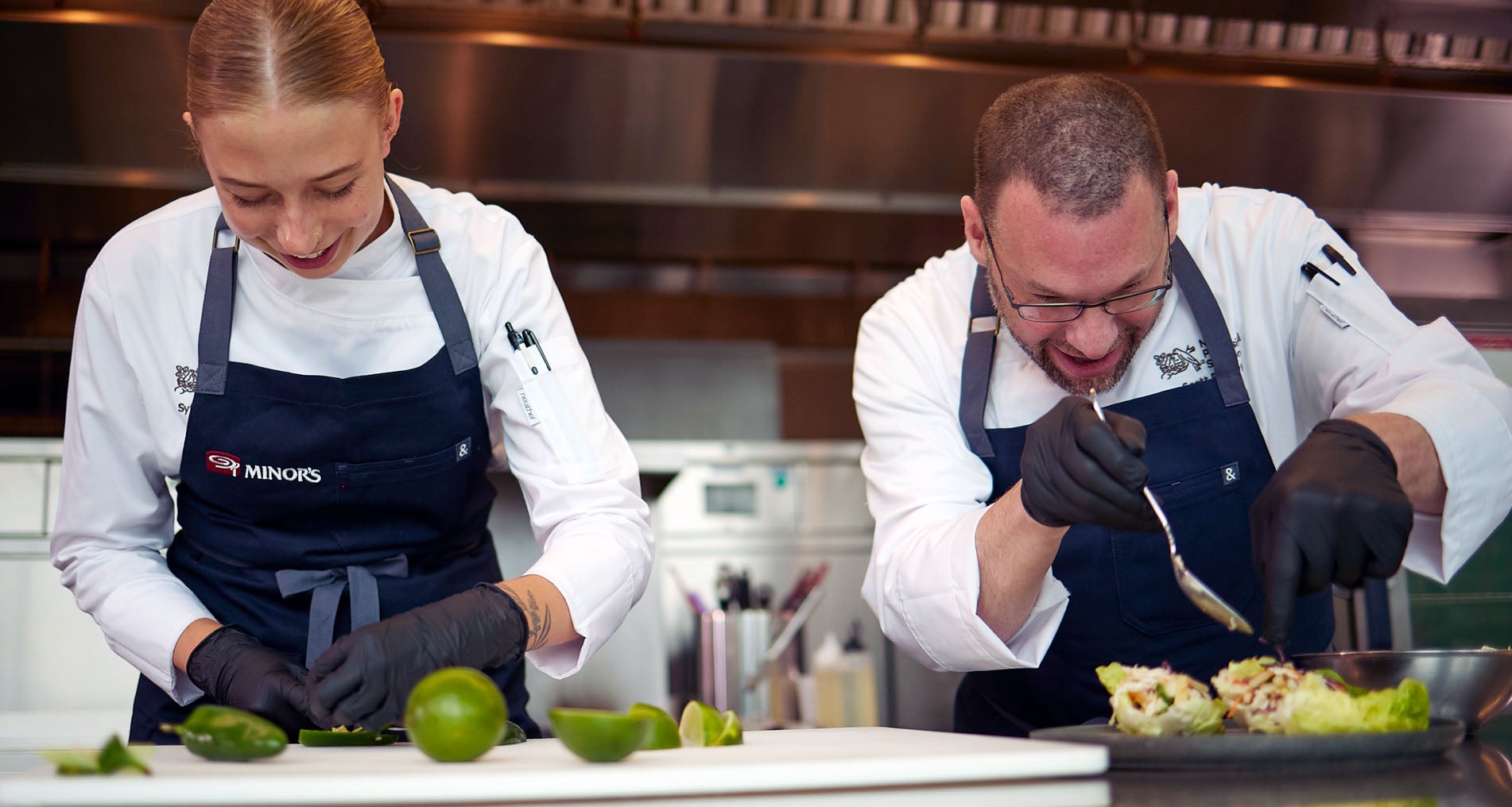 Chef SyEnna and Chef Popovic working side-by-side in the kitchen