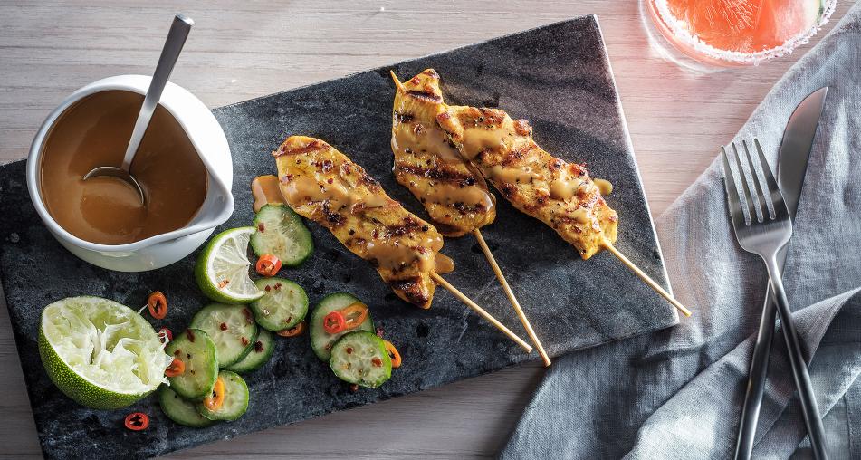 Chicken skewers with sauce and cucumbers