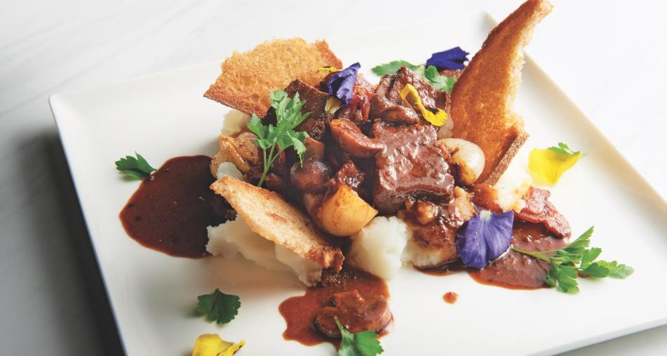 Beef Bourguignon Toast on a plate with colorful garnish