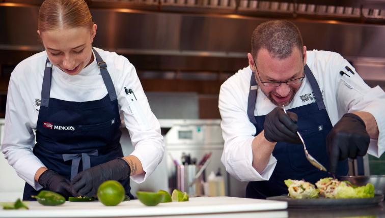 Chef SyEnna and Chef Popovic working side-by-side in the kitchen