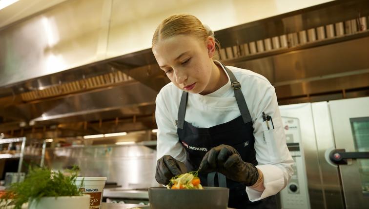 Chef SyEnna puts the finishing touches on a prepared dinner salad.