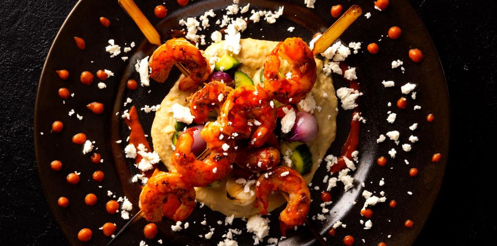 Grilled Harissa Shrimp Skewer with Hummus, Cucumber, Mint, Charred Onion, and Feta
