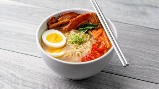 Spicy Pork Ramen Broth in a bowl with silver chopsticks resting on top