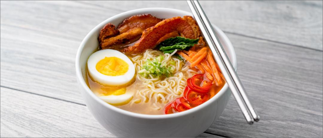 Spicy Pork Ramen Broth in a bowl with silver chopsticks resting on top