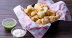 Country Fried Basil Pesto Cauliflower Bites in a takeout-style container with pesto and sour cream on the side