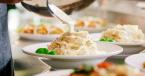 A person spooning vegan alfredo sauce from a pan onto a dish